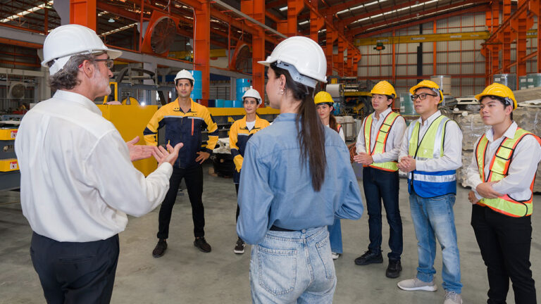 Factory supervisor addressing workers during a safety briefing inside a warehouse