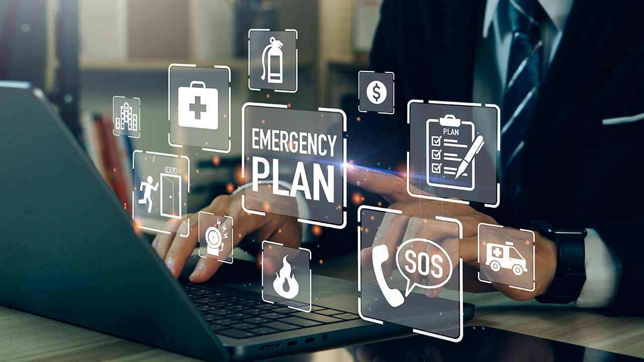 Businessperson using a laptop surrounded by digital emergency plan icons