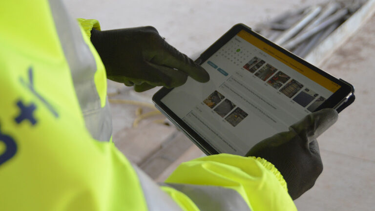 Construction worker using a tablet to review site inspection photos and reports