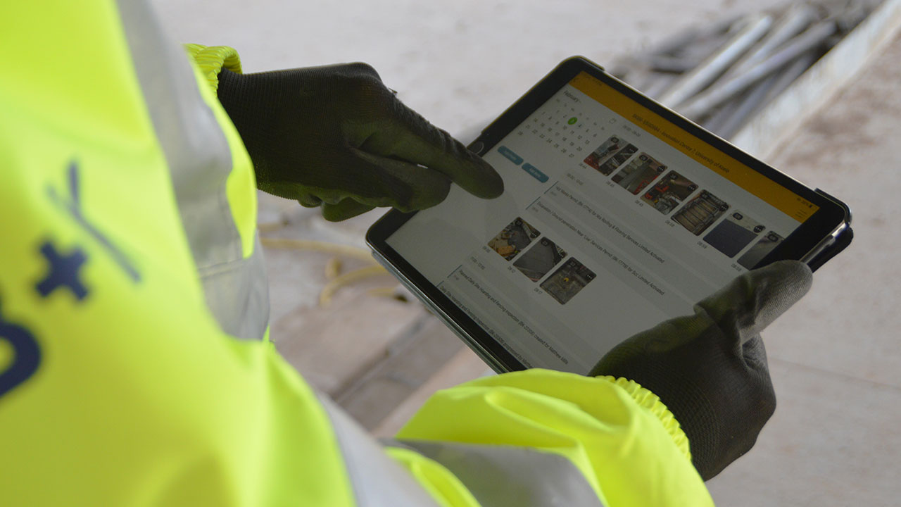 Construction worker using a tablet to review site inspection photos and reports