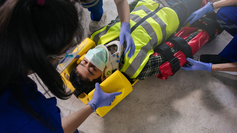 Emergency responders assisting an injured worker wearing safety gear