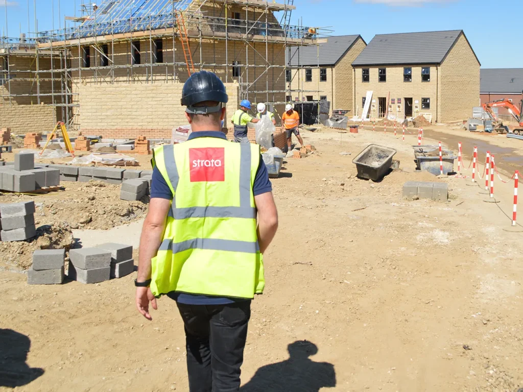 Construction site with workers in safety gear and houses under construction