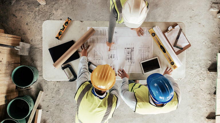 Construction team reviewing blueprints on a table at a building site