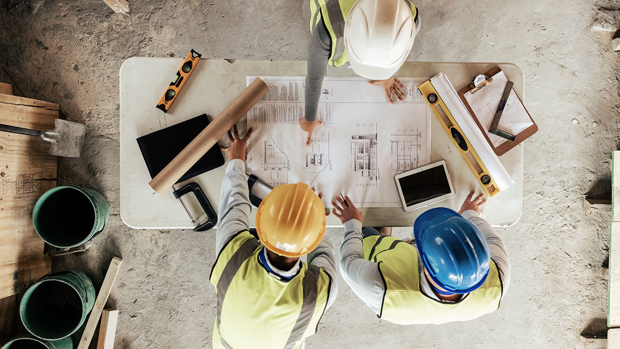 Construction team reviewing blueprints on a table at a building site