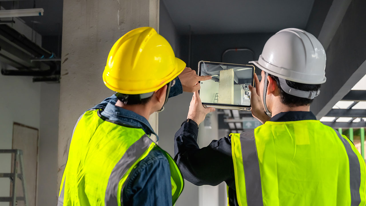 Engineers using a tablet to inspect a building site interior