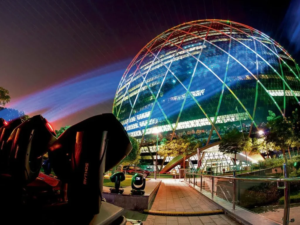 Night view of a dome-shaped building lit with colourful lights and spotlights