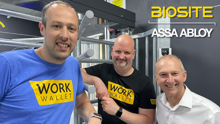 Three men smiling at an industrial entry gate
