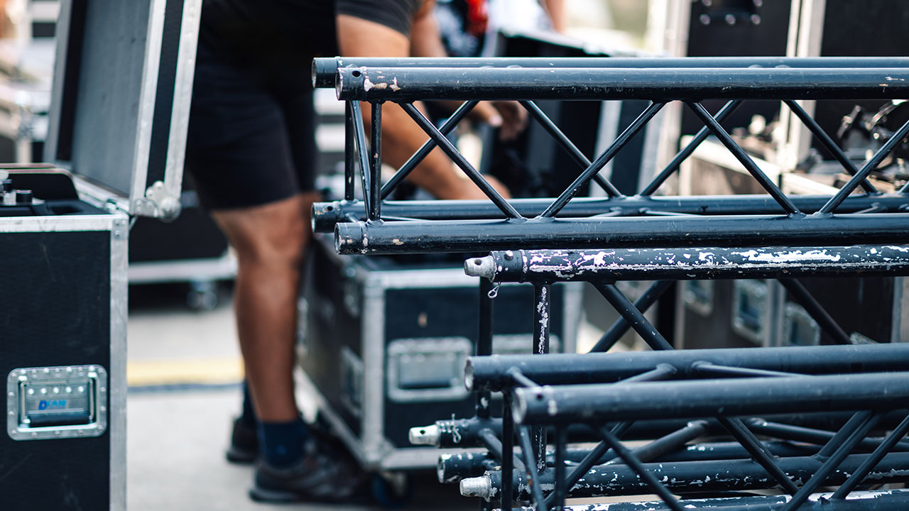 Worker assembling or packing metal stage trusses and equipment cases