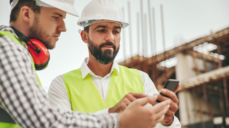 Two construction managers reviewing information on a smartphone