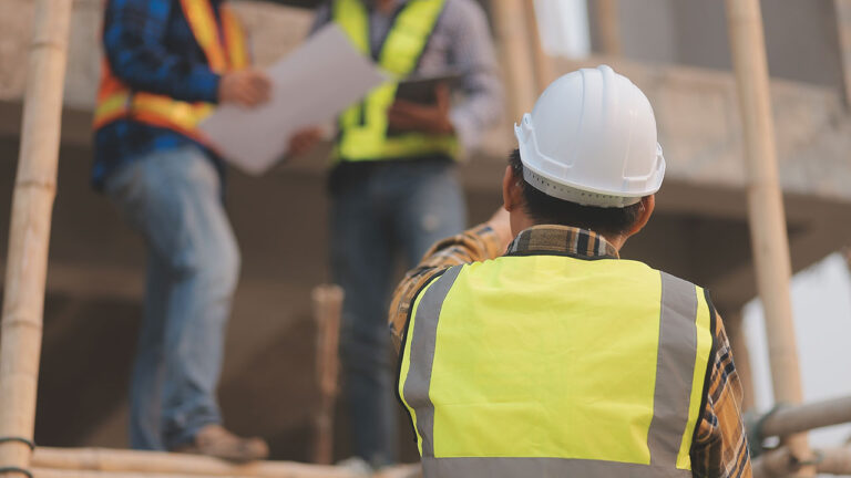 Construction supervisor giving directions to workers on scaffolding
