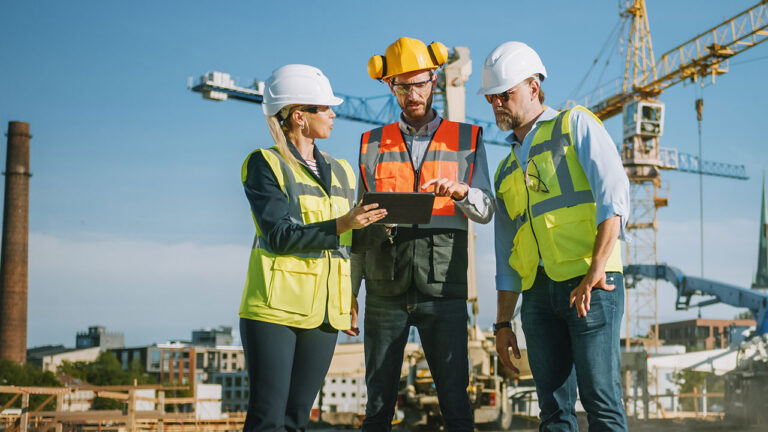 Engineers at construction site reviewing plans on a tablet