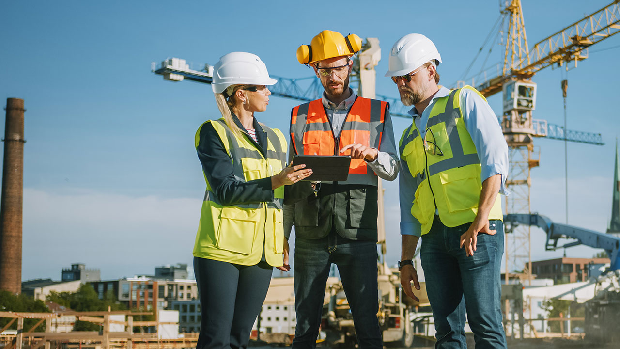 Engineers at construction site reviewing plans on a tablet