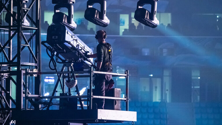 Stage technician operating a spotlight on elevated scaffolding during an event