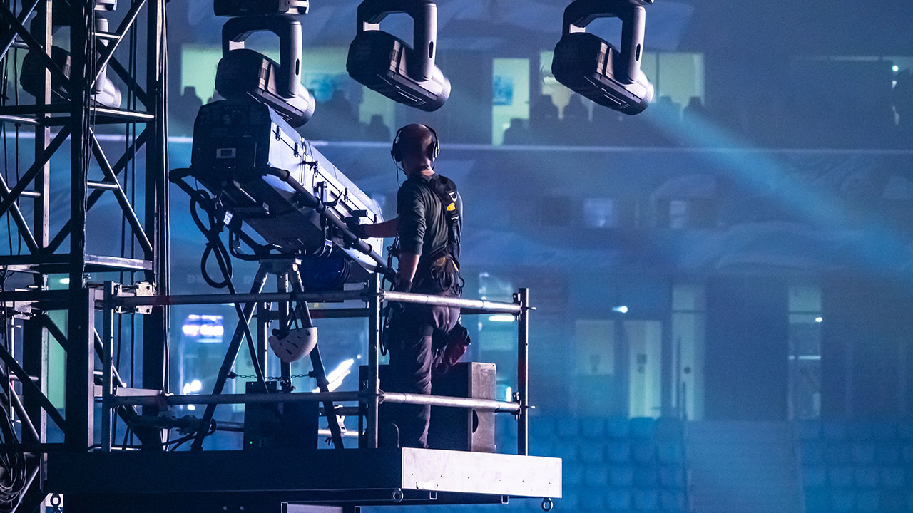 Stage technician operating a spotlight on elevated scaffolding during an event