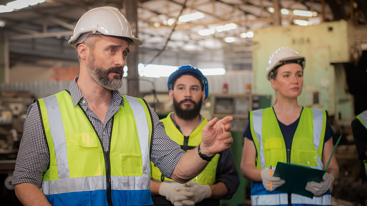 Site supervisor leading a safety briefing with team members in helmets