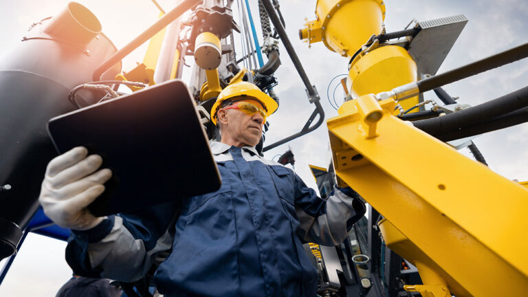 Engineer with tablet inspecting heavy industrial machinery