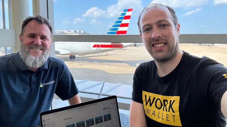 Two people with laptop at airport showing Work Wallet dashboard on screen