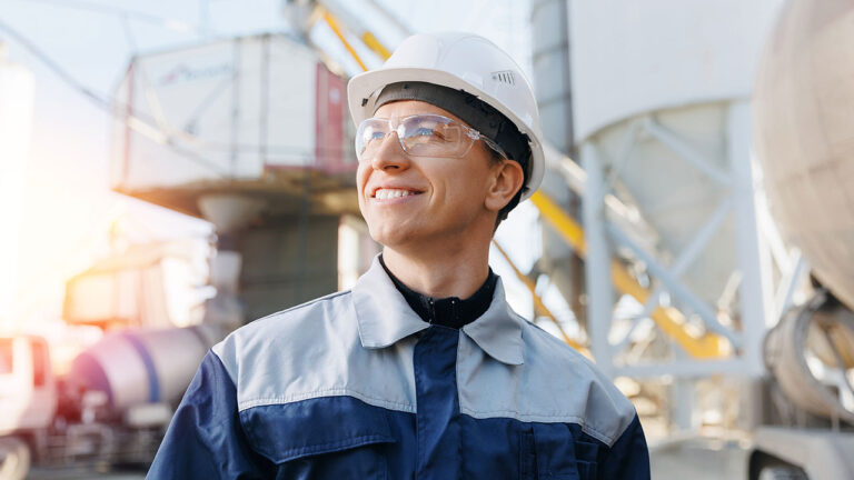 Smiling construction worker in hard hat at industrial site