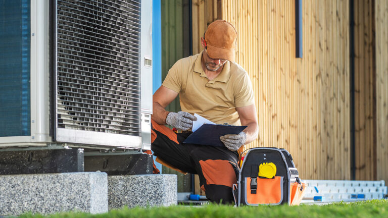Technician checking outdoor HVAC unit and filling out inspection form