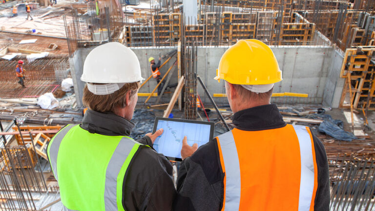 Two site supervisors using a tablet to review construction project progress