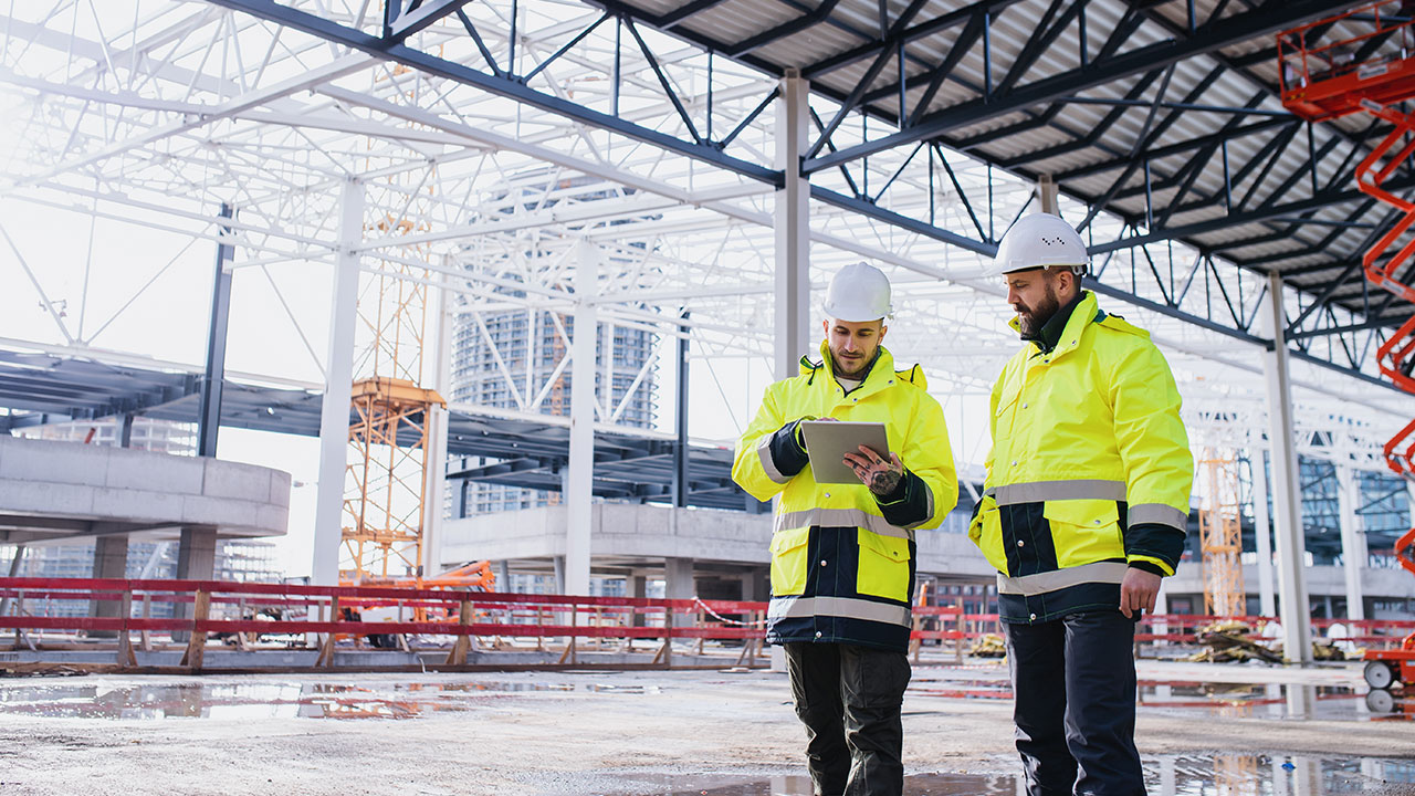 Construction managers reviewing plans on a tablet at a building site