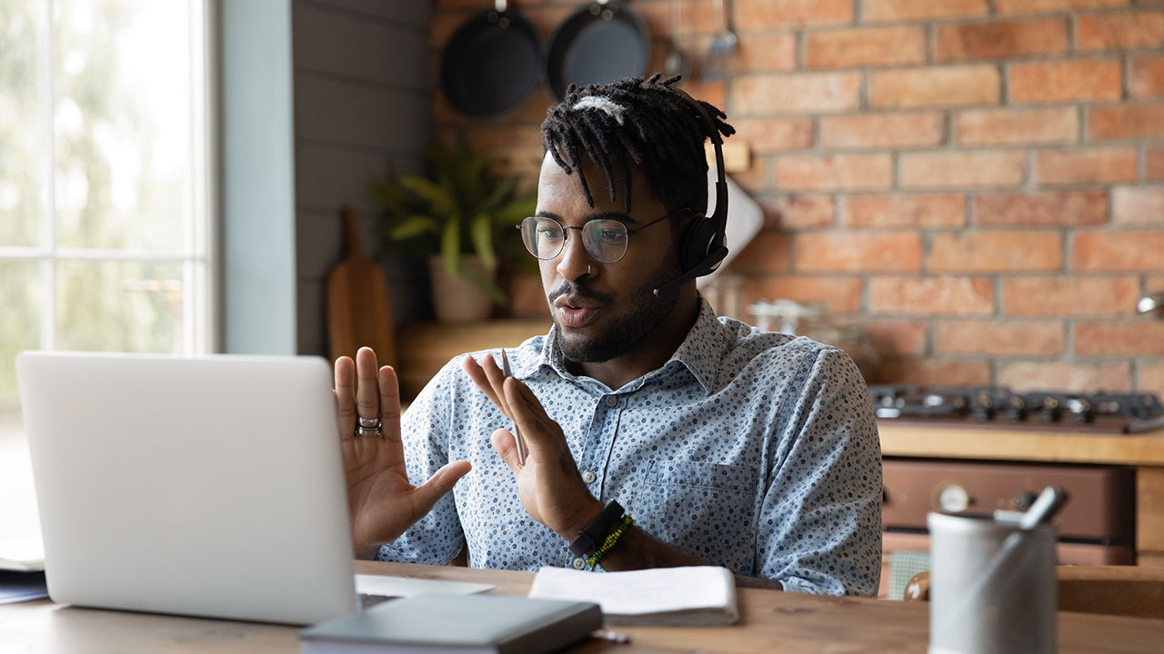 Person on a video call wearing a headset and gesturing while working remotely