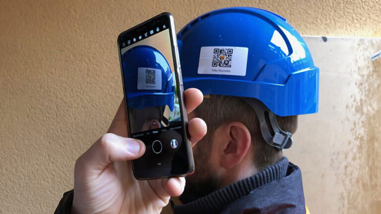 A person scans a QR code on a blue safety helmet using a smartphone