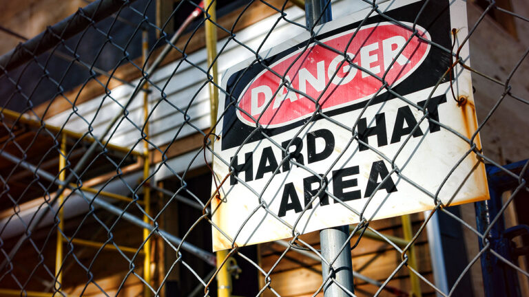 Danger Hard Hat Area sign on a construction site fence