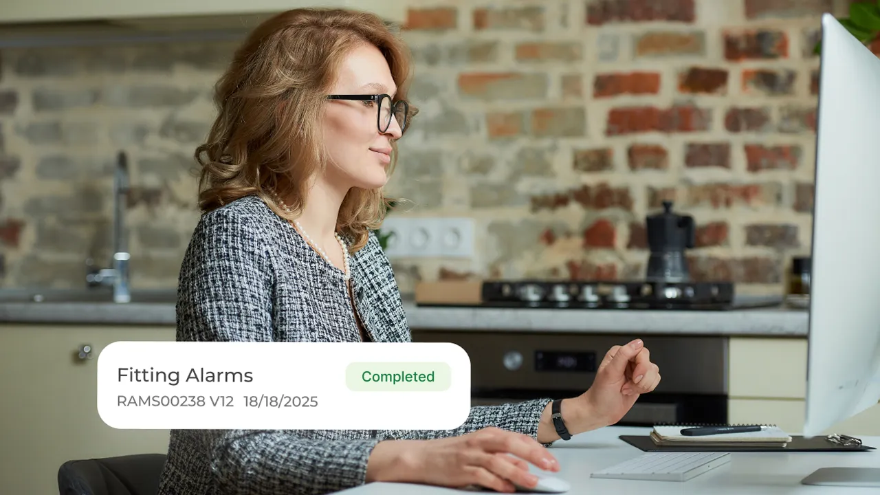 Person working at a computer with a completed task labelled "Fitting Alarms"