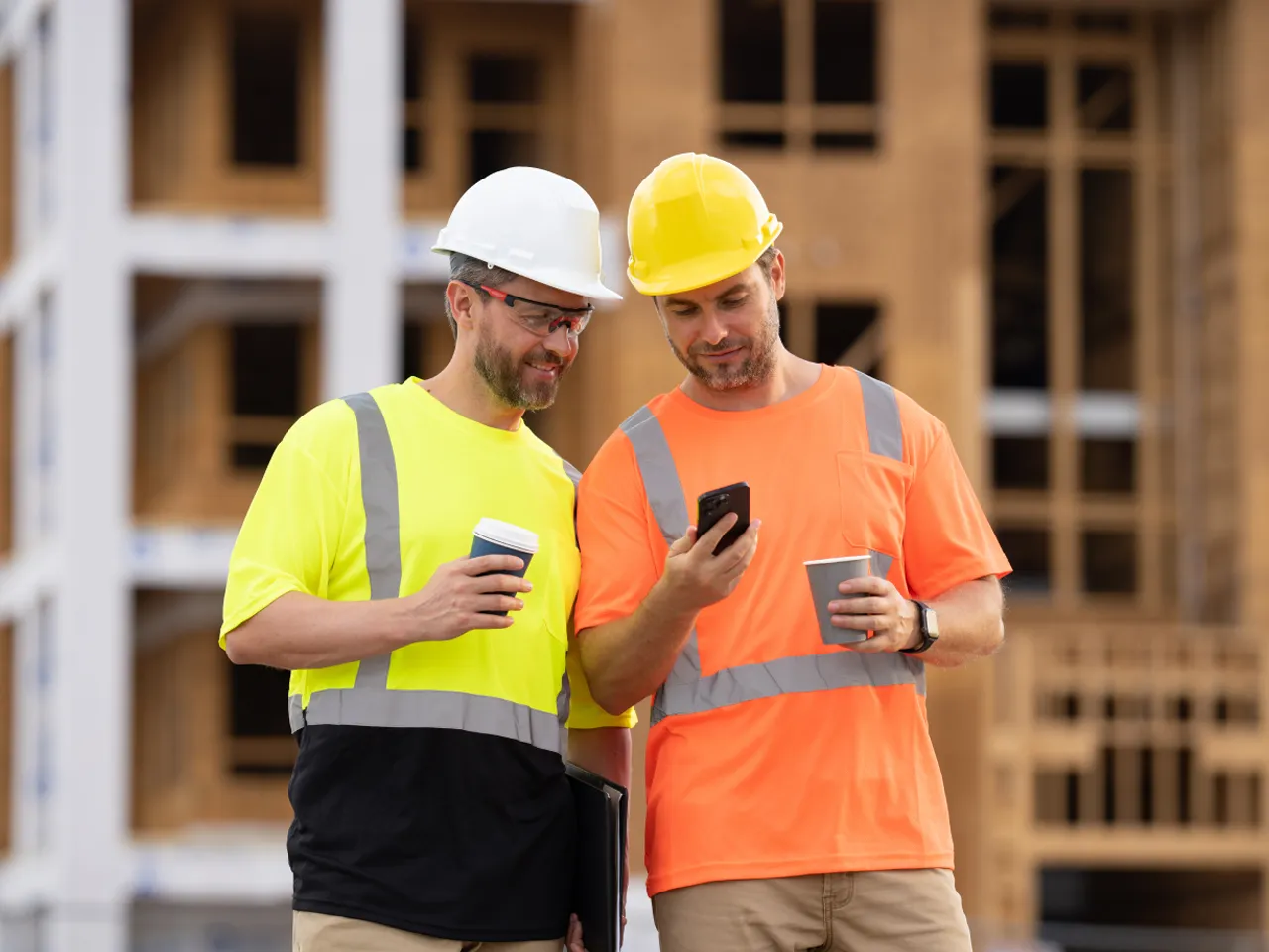 Construction workers drinking coffee and viewing a phone on-site