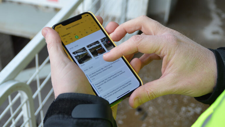 A person uses the Work Wallet smartphone app to review site inspection photos