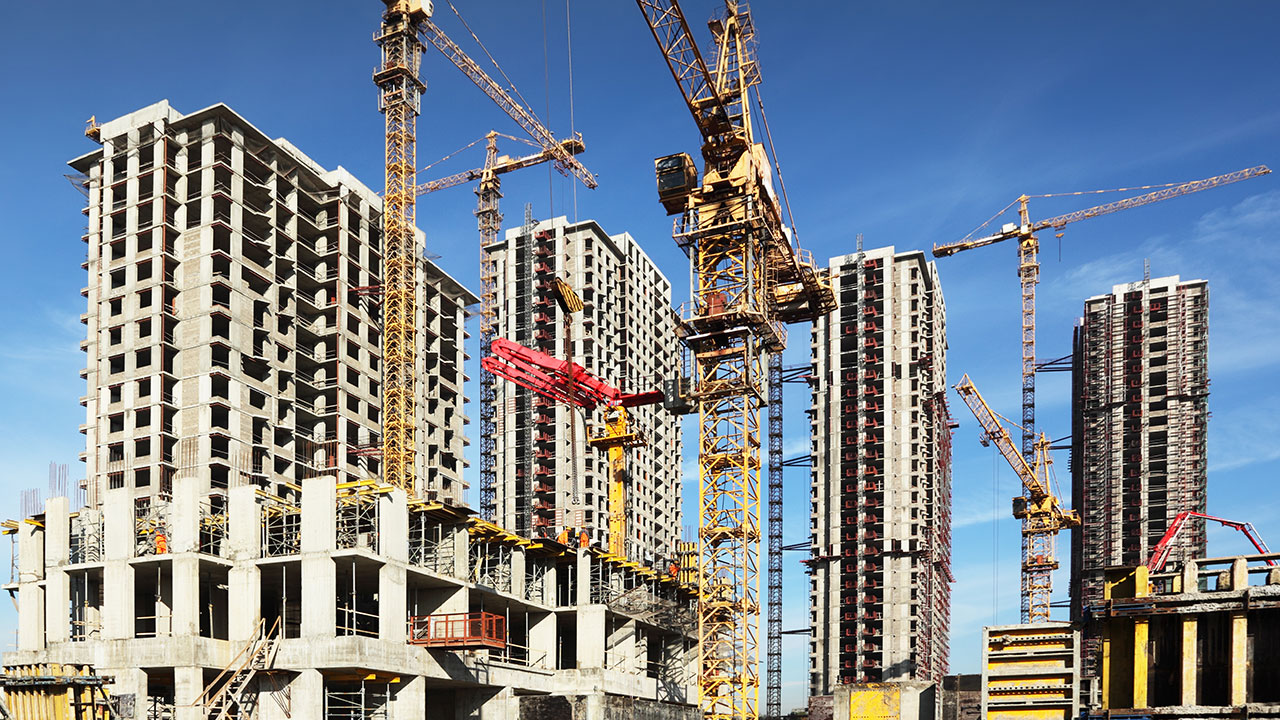Tall buildings under construction surrounded by multiple cranes