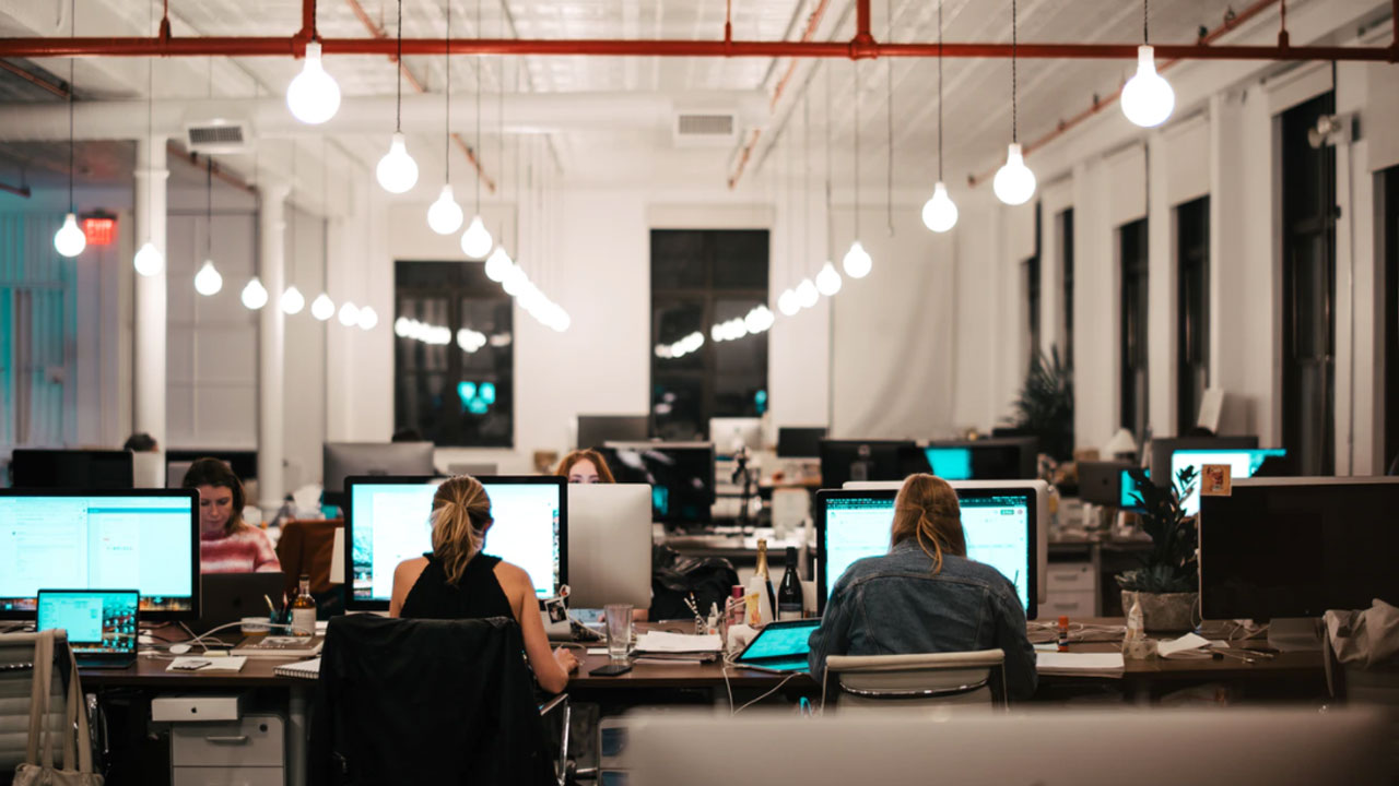 People work at computers in a modern open-plan office