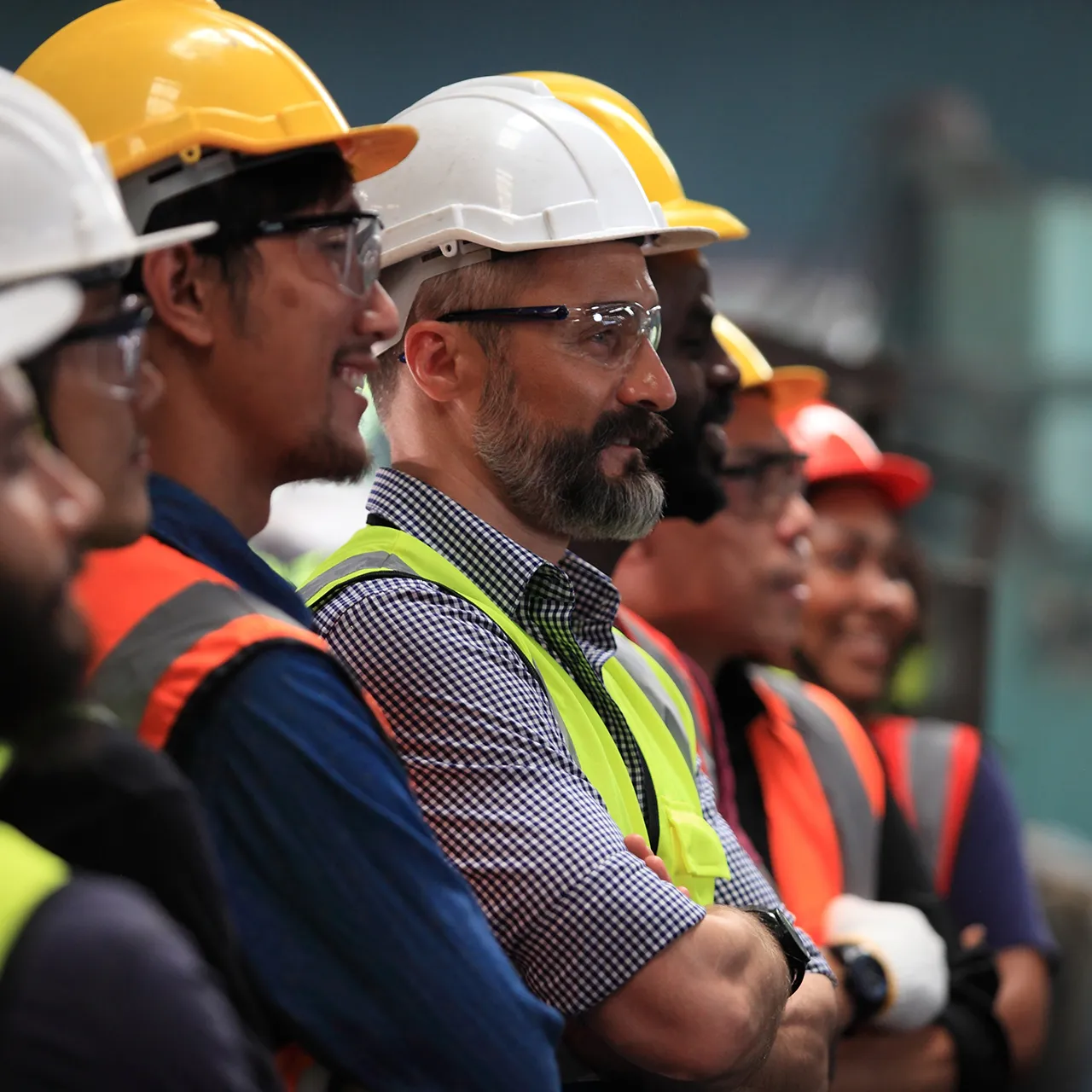 Team of site workers wearing hard hats and safety vests during a briefing
