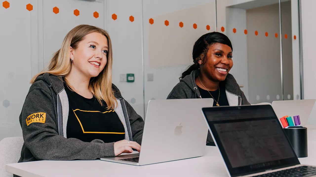 Two Work Wallet team members smiling during a meeting with laptops