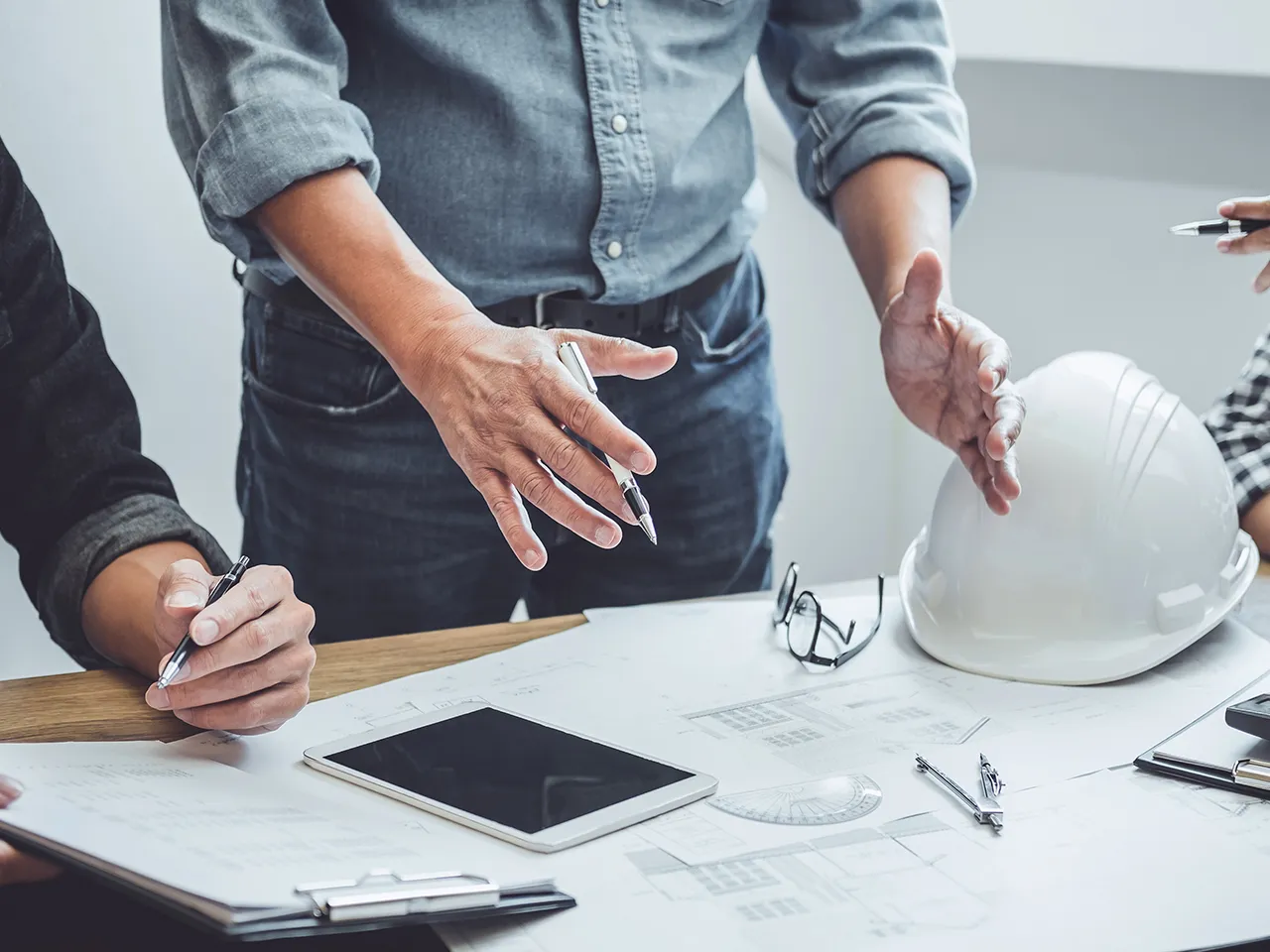 Team at a table with a hard hat, tablet, and papers