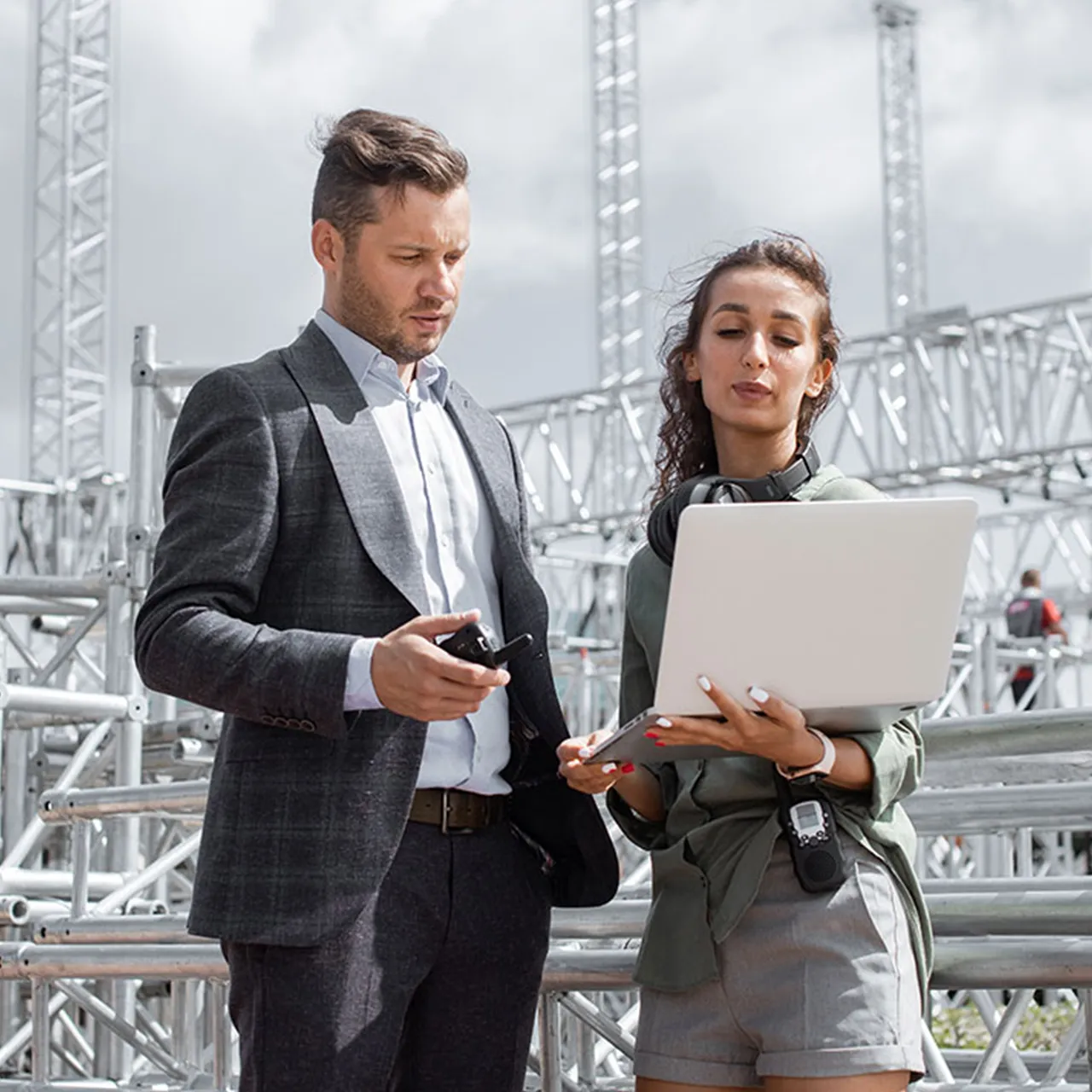 Two professionals managing an event site using a laptop and radio