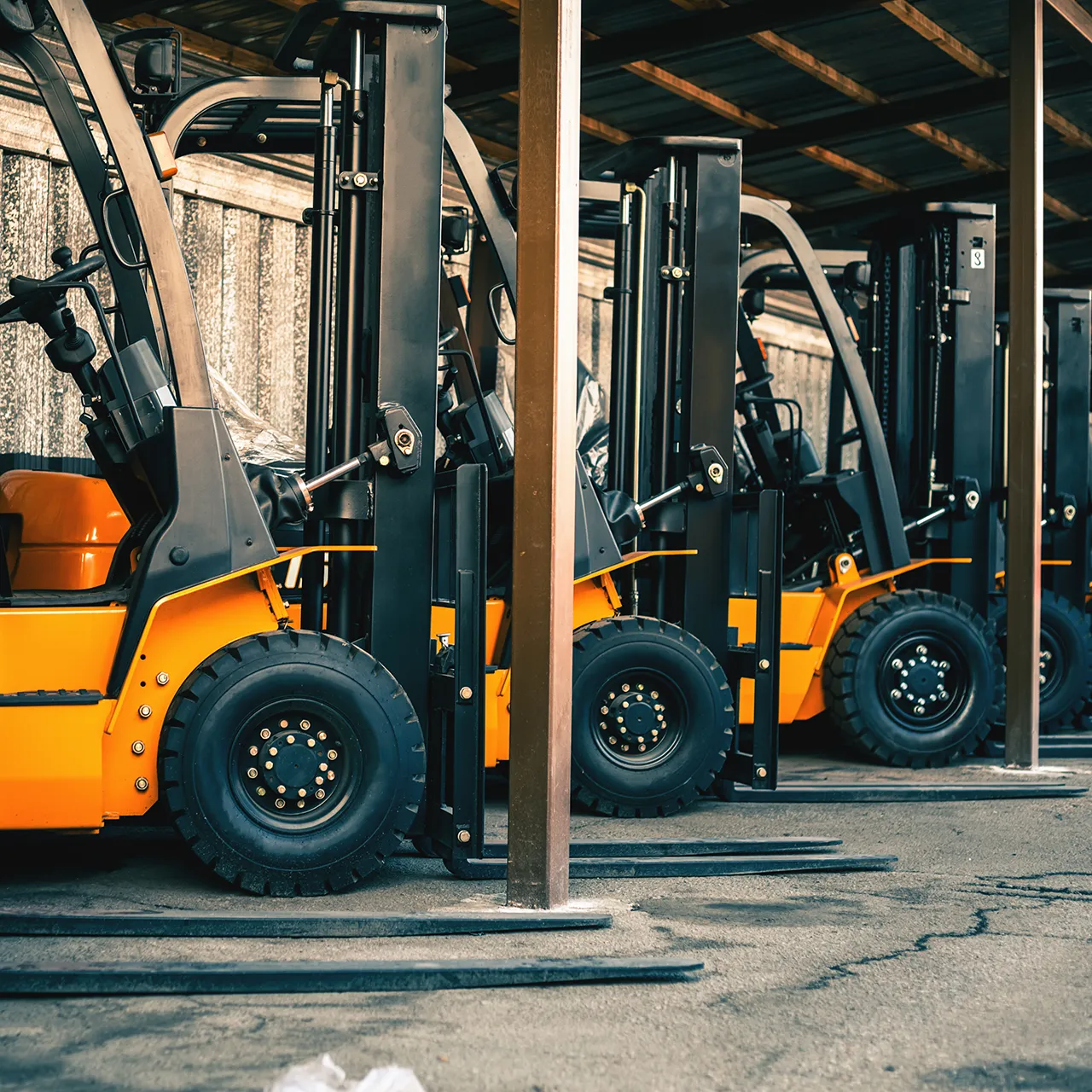 Multiple yellow forklifts lined up in an industrial storage area