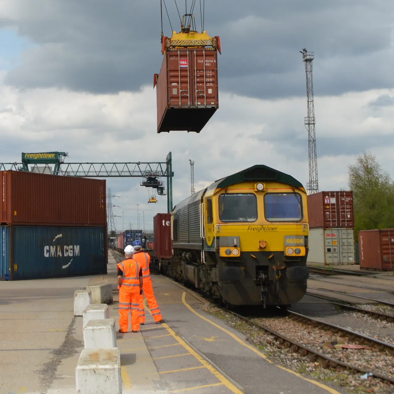 Freightliner train being loaded with shipping containers at a rail yard