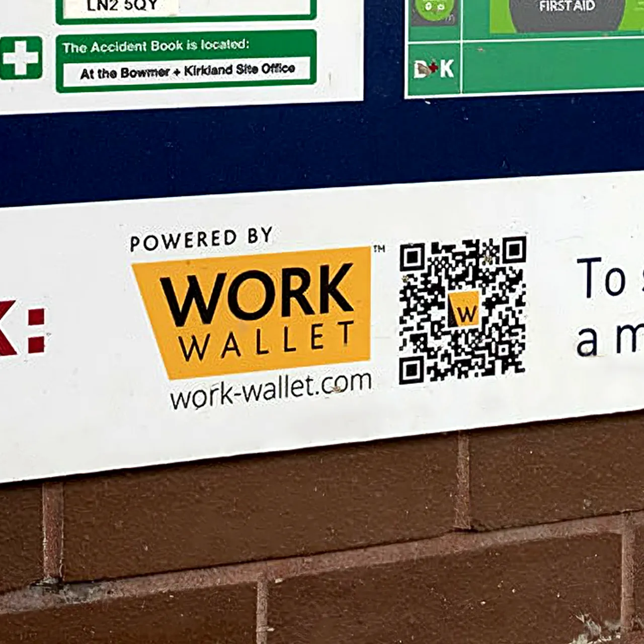 Construction safety sign featuring Work Wallet branding and QR code on a brick wall