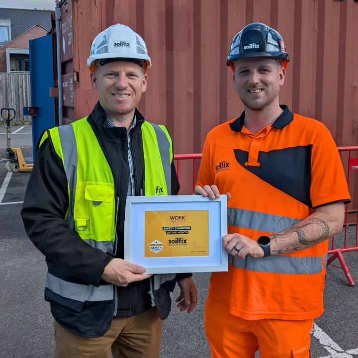 Two Soilfix workers in safety gear holding a Work Wallet Safety Champion award