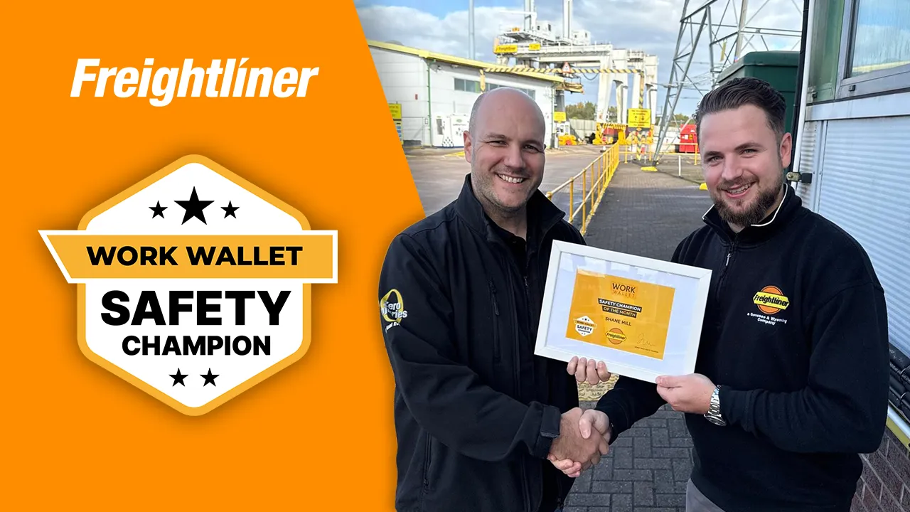 Two Freightliner employees shaking hands while holding a Work Wallet Safety Champion award