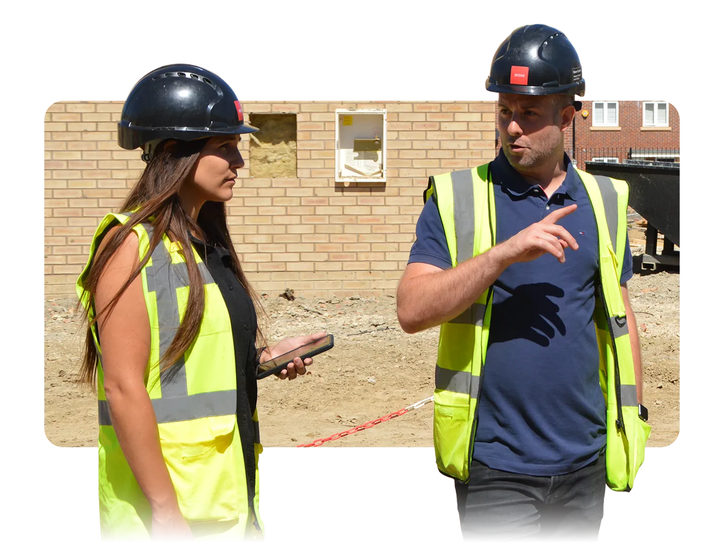 Construction managers in high-visibility vests discussing work on a building site