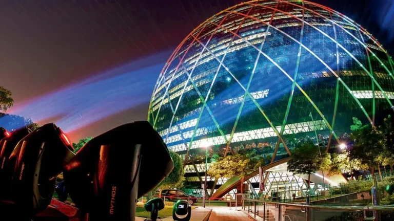Night view of a dome-shaped building lit with colourful lights and spotlights