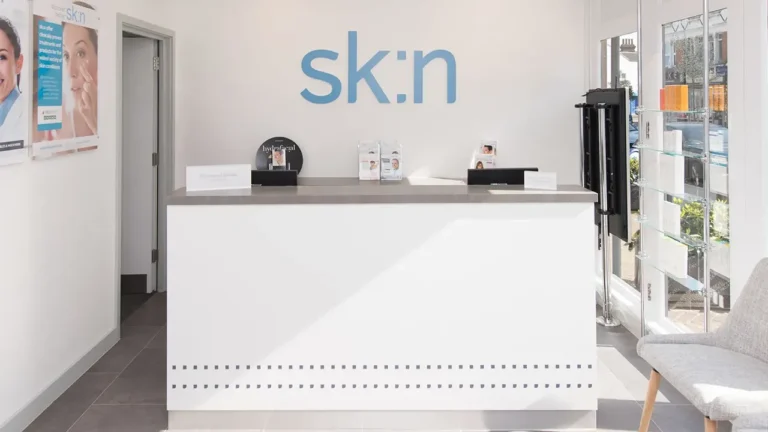 Bright reception area with "sk:n" logo on the wall and modern white counter