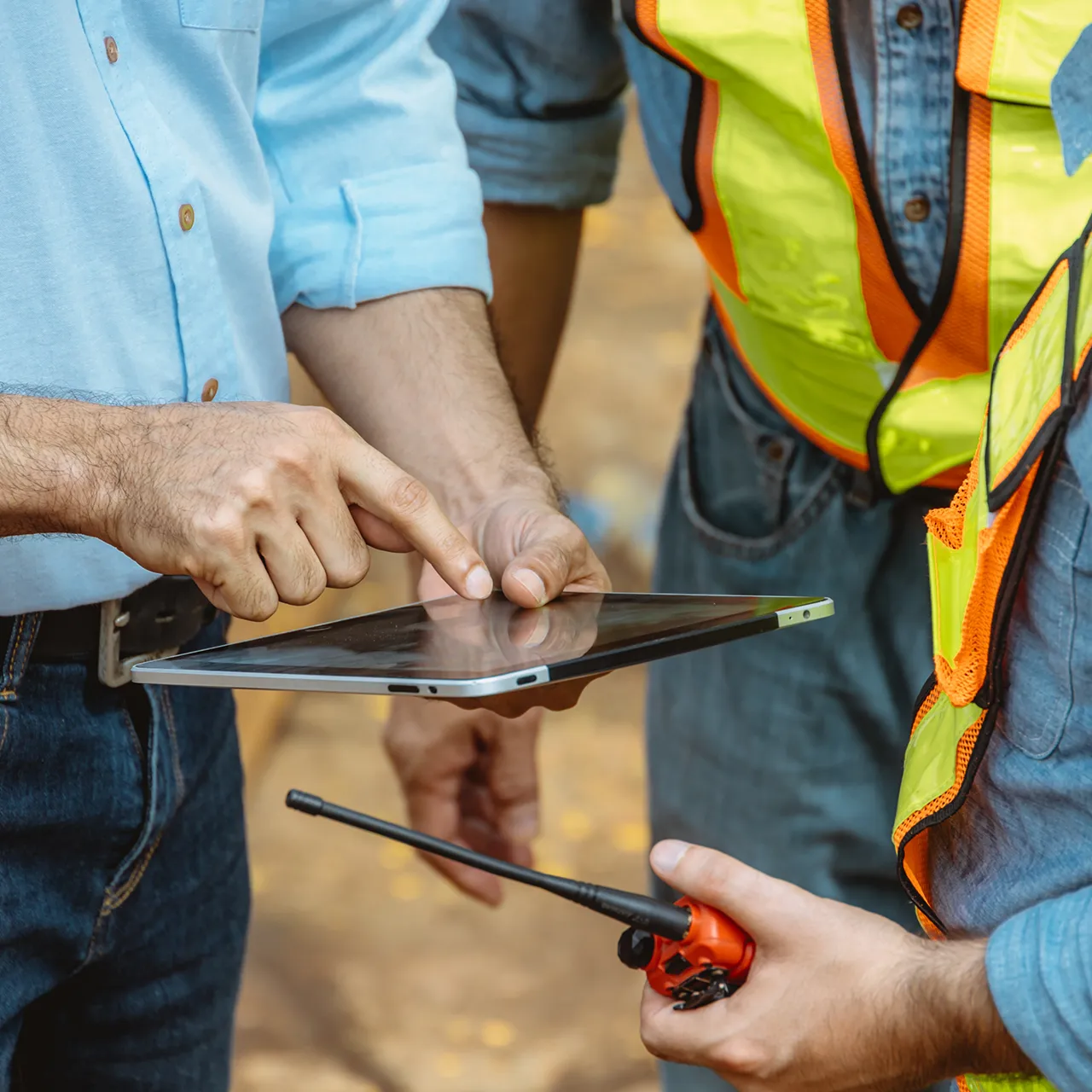 Closeup of workers checking a tablet and holding a radio