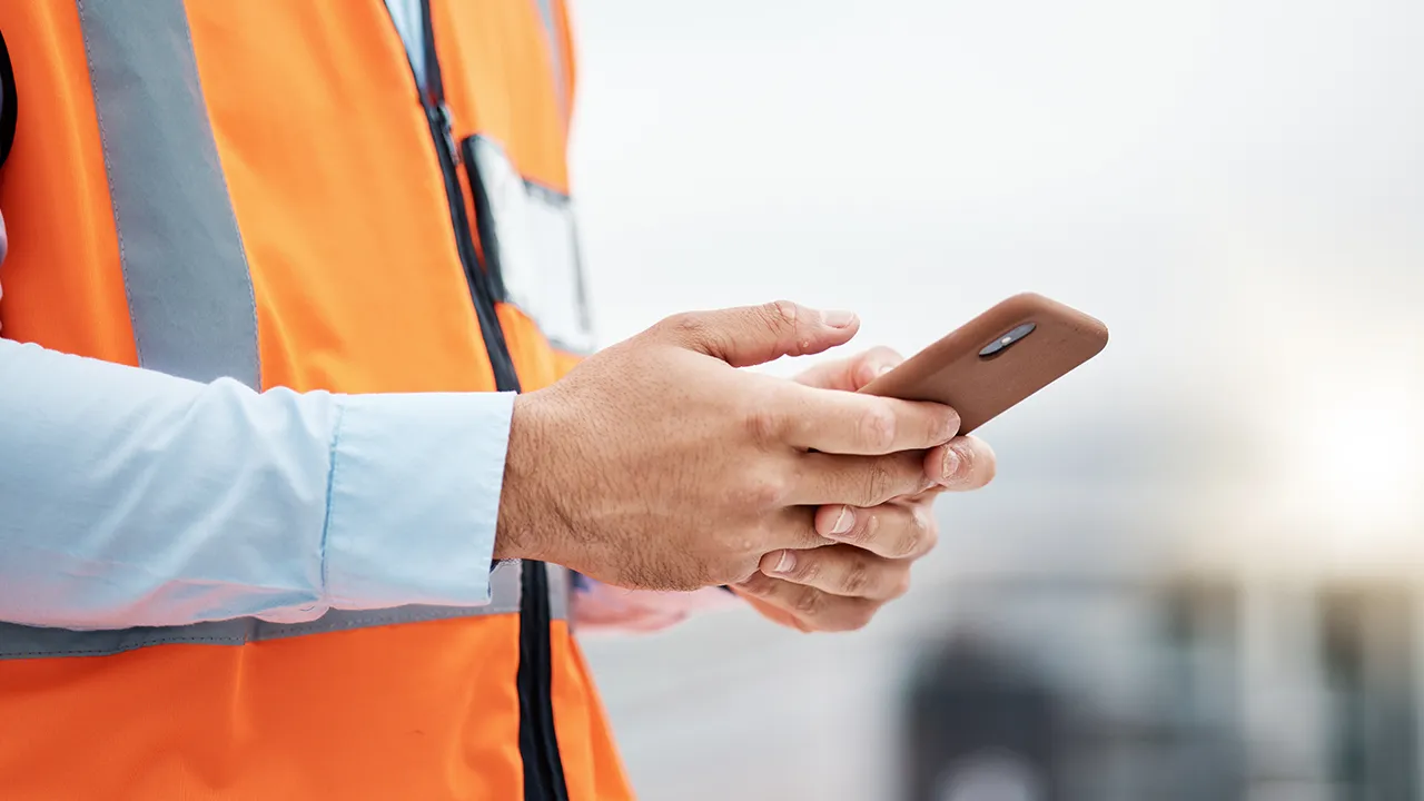 Worker in orange safety vest using smartphone