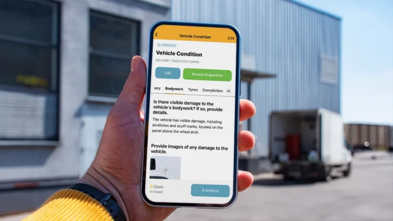 Hand holding a smartphone displaying a vehicle condition inspection.